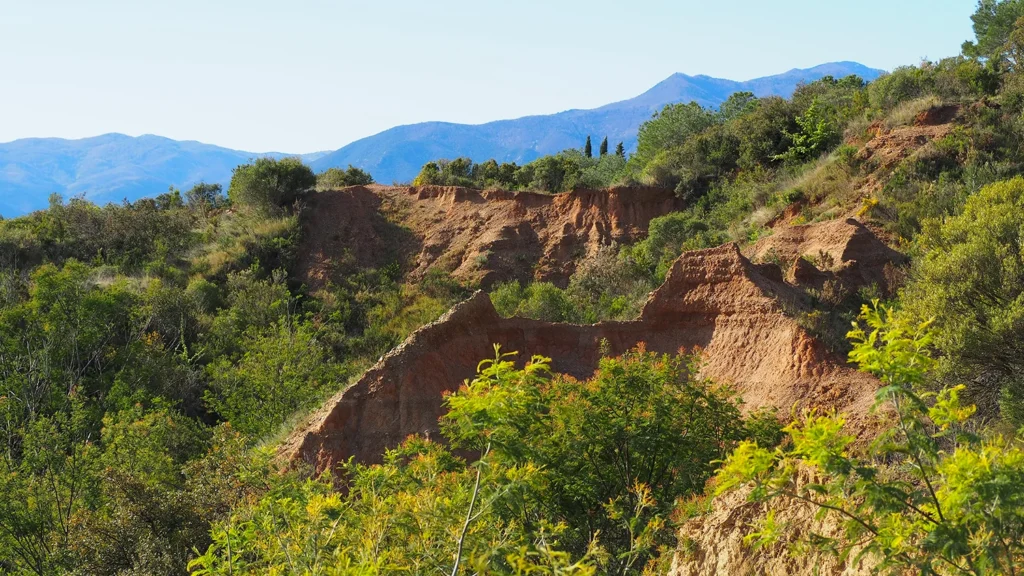 Falaises d'argile rouge entourées de végétation méditerranéenne dans les Pyrénées-Orientales