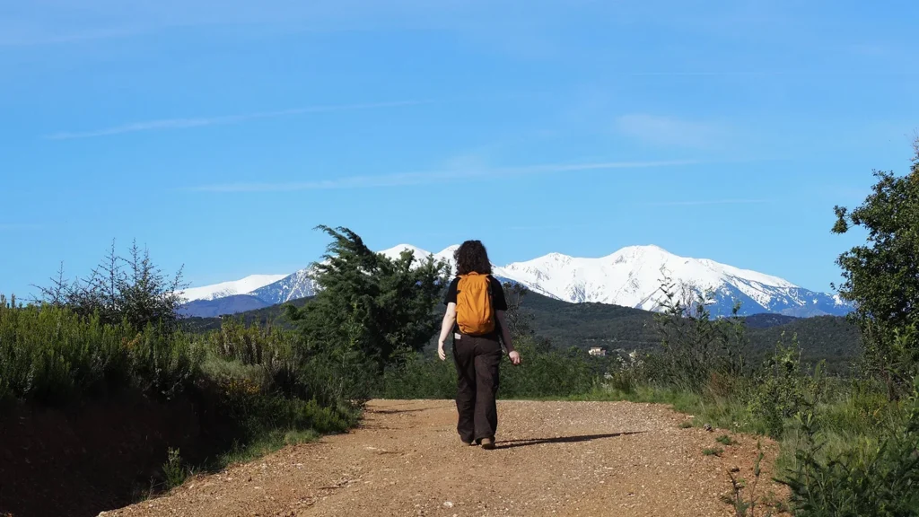 Alix céramiste de dos marchant vers le Canigou enneigé dans les Pyrénées-Orientales